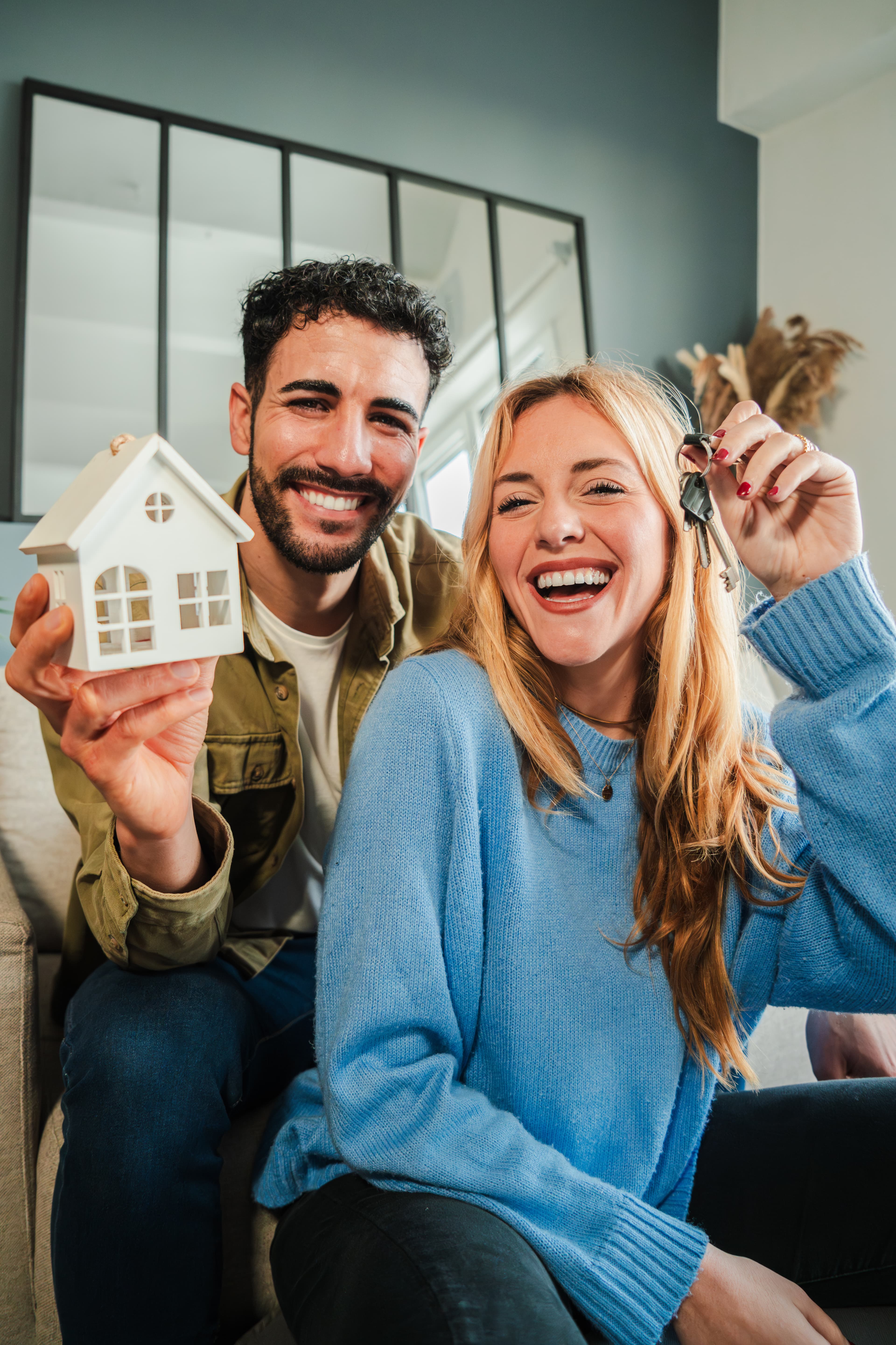Homebuyer holding keys in front of a new home